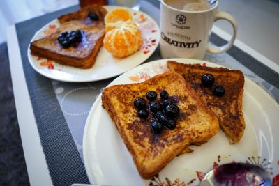 A plate of french toast covered in blueberries, alongside a mug of coffee.