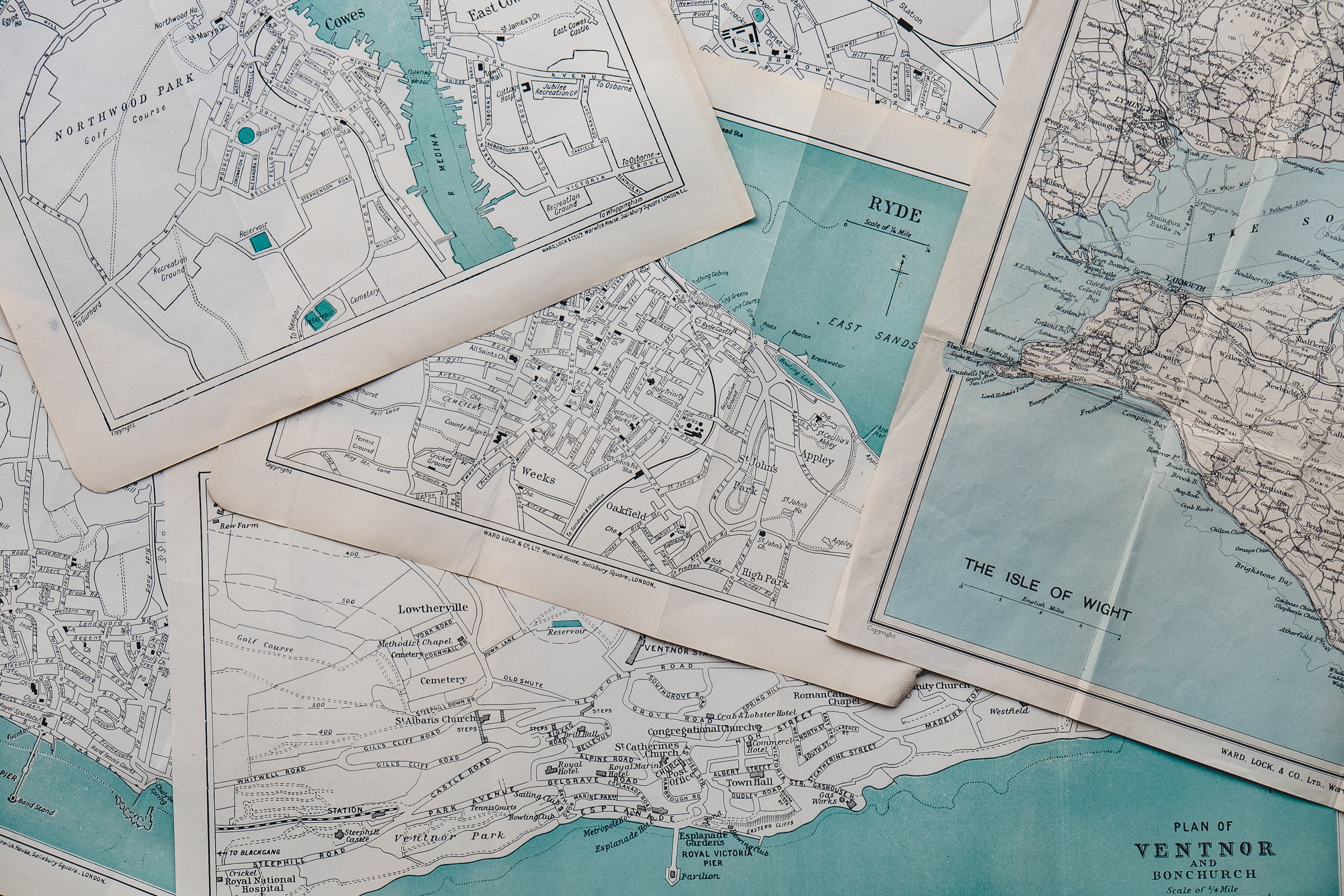 Image description: several paper maps showing roads, bodies of water, and place names for different geographical areas. Photo credit to Annie Spratt of Unsplash.