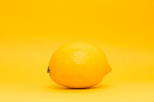 A bright yellow lemon in front of a yellow background.