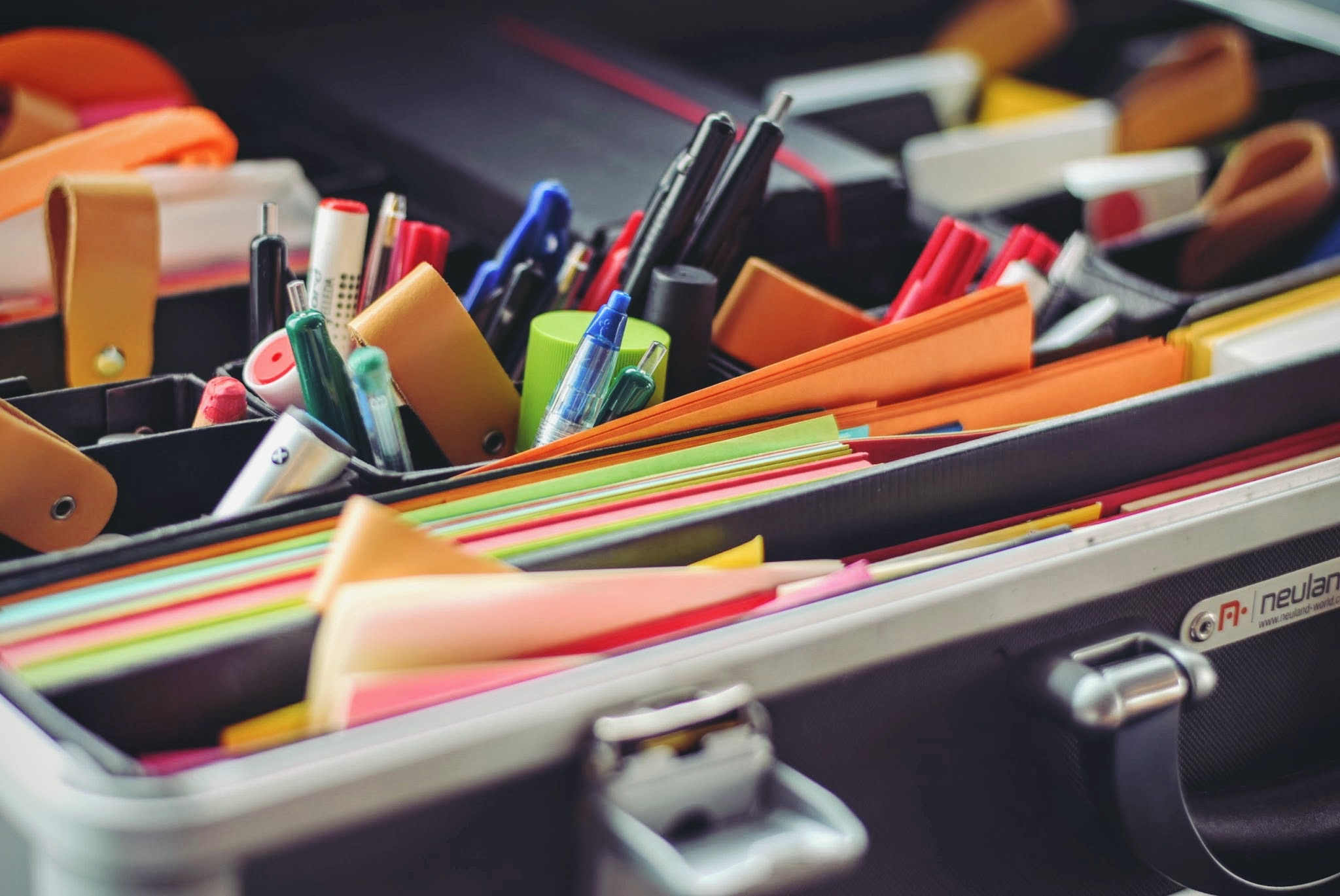 Box of sticky notes, pens, and pencils.