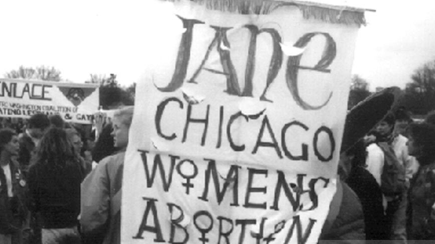 Black and white photo of a Jane Collective sign at a rally.
