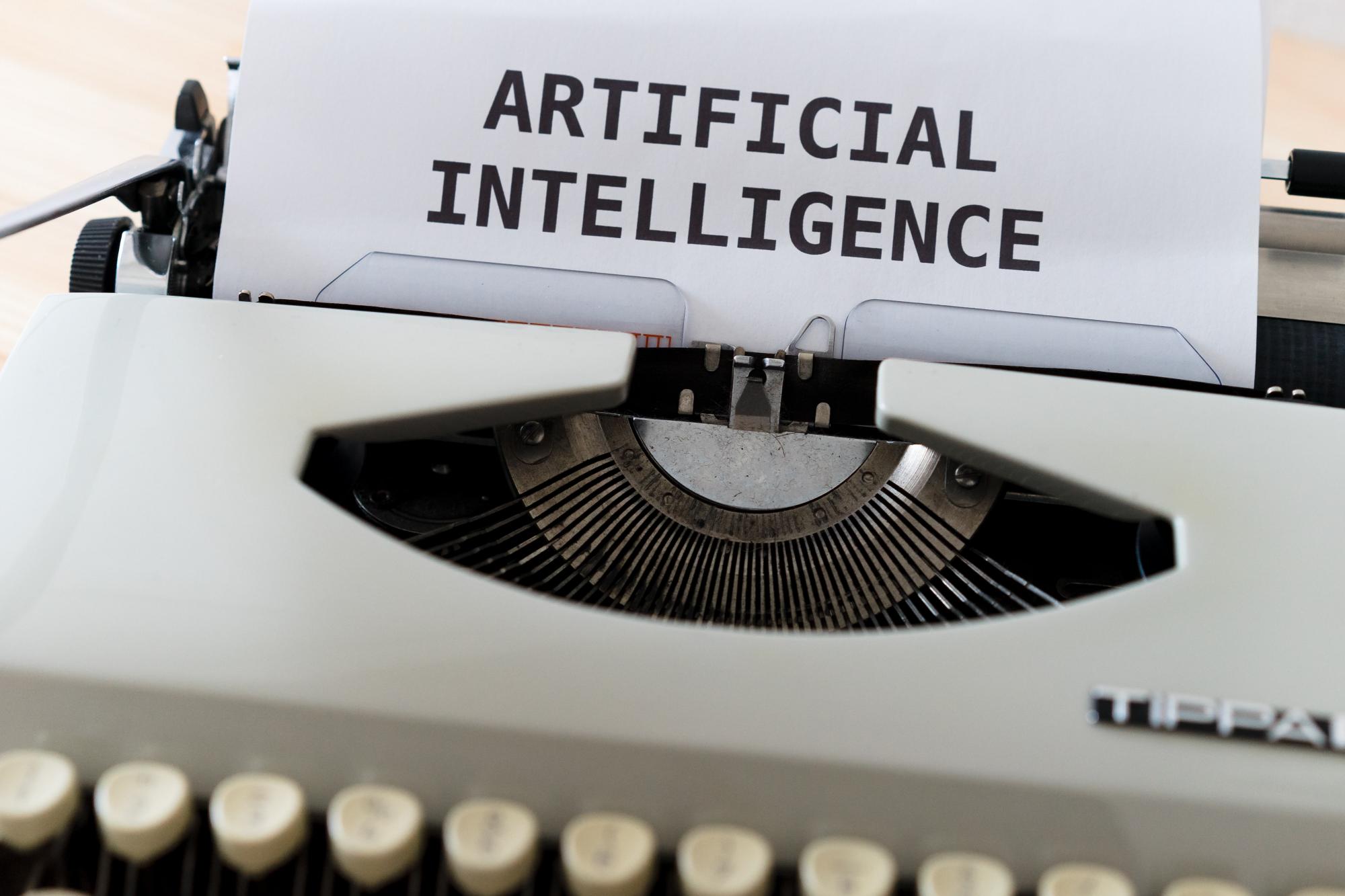 Image of a typewriter with the words "artificial intelligence" typed onto a piece of paper.