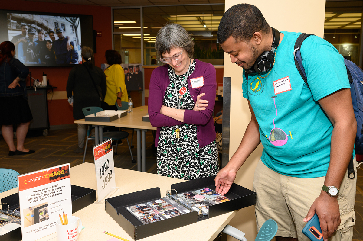 Archivist Emily Davis looks at a photo album with Dontavious Sippial, a PhD student in Chemical Engineering.