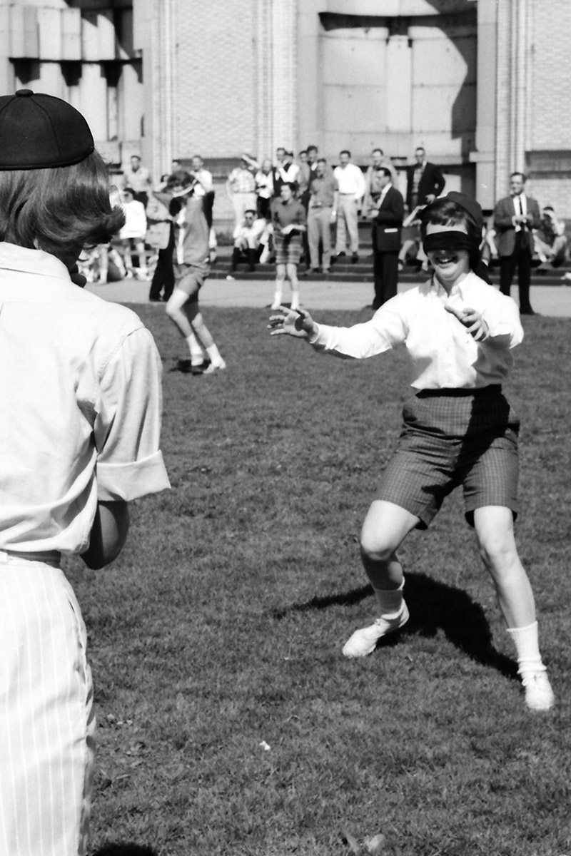 Two women college students and members of an unidentified sorority take part in the 'Catch the Robber' sorority race (of which blindfolds are used) on the CFA lawn. The race is part of the Spring Carnival Sorority Relays.