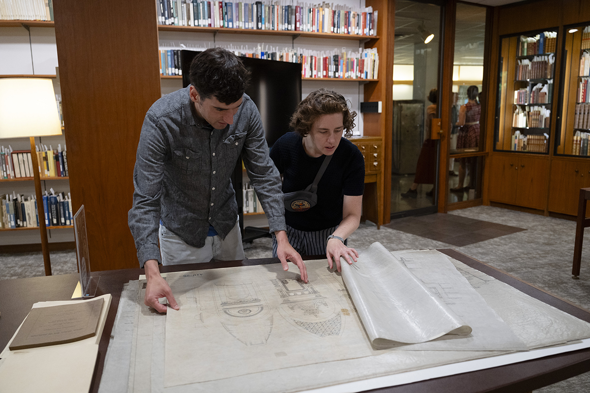 Matthew Huber and Digital Projects and Publishing Specialist Talia Perry  examine architectural drawings in the Fine and Rare Book Room.
