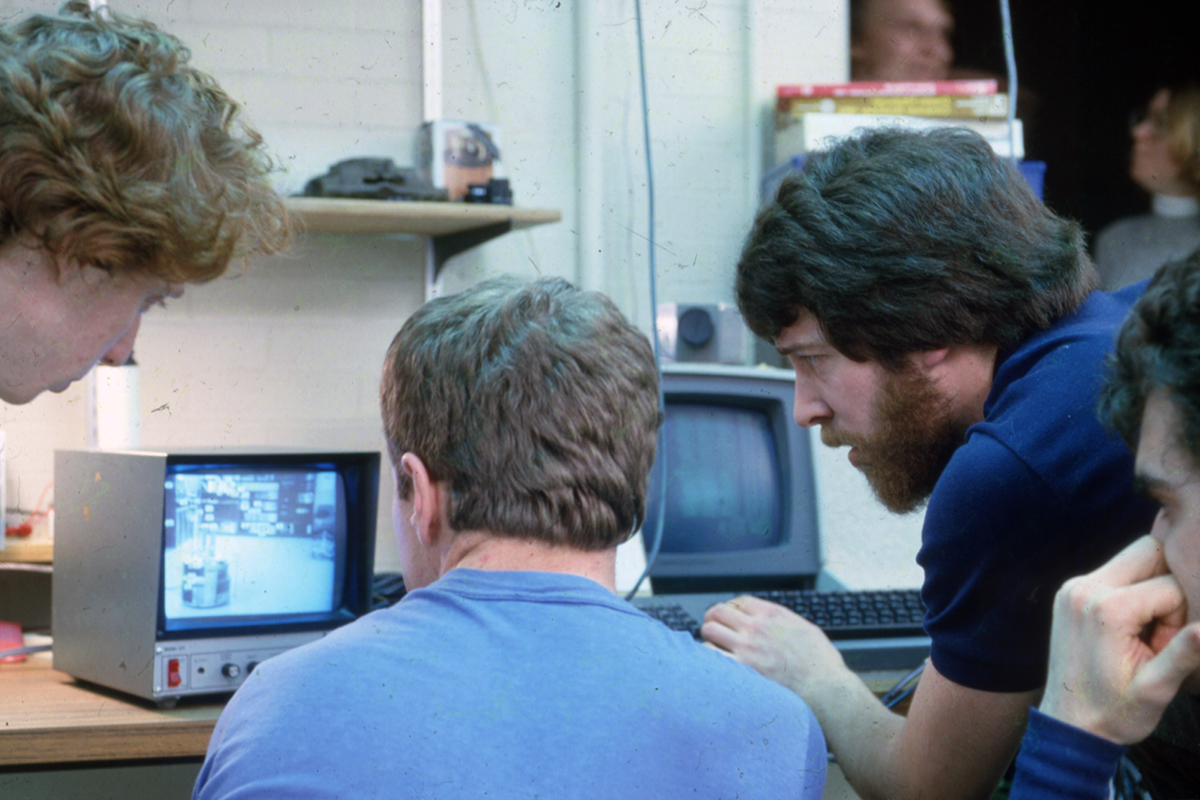 Kevin Dowling, Chuck Thorpe, and Larry Matthies study video feed of the Pluto robot in the Mobile Robots Laboratory. From the Robotics Institute Records, 0000-0018.