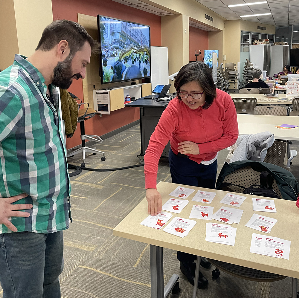 Arts and Humanities Librarian Lynn Kawaratani helps Overnight Library Assistant Patrick Hannay find a fortune based on his zodiac animal.