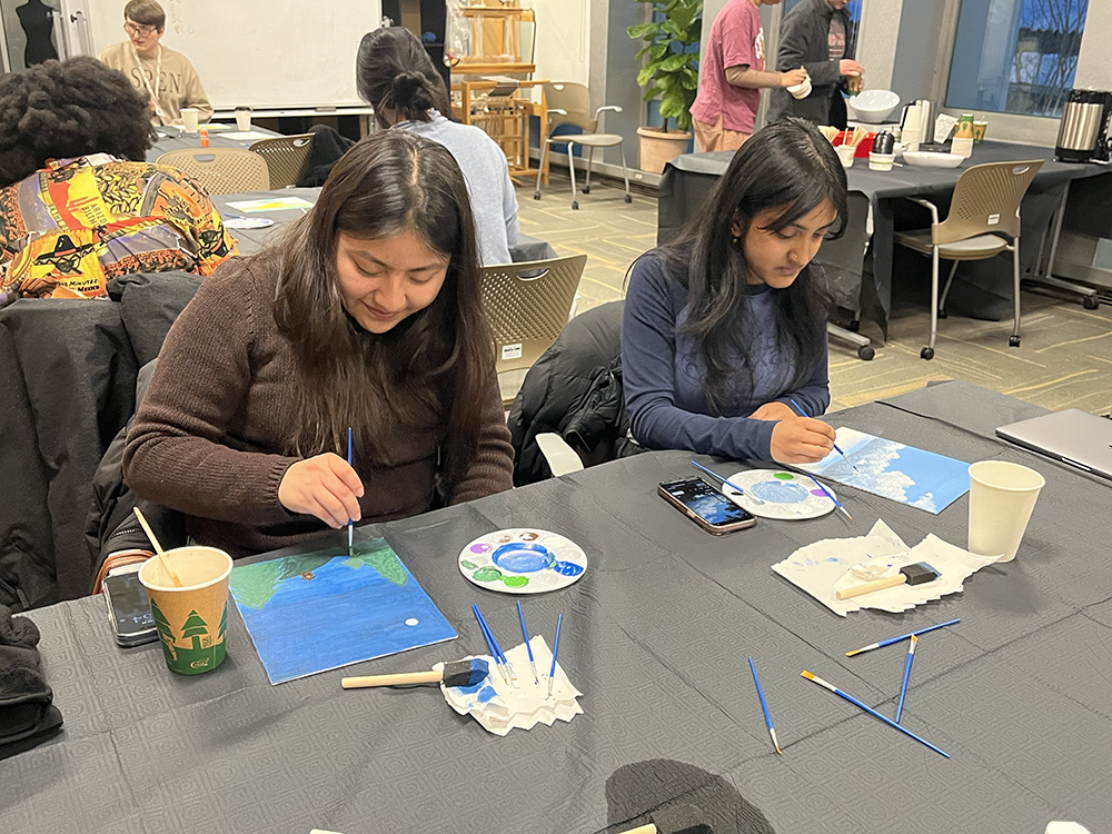 Two participants concentrate on their original paintings.